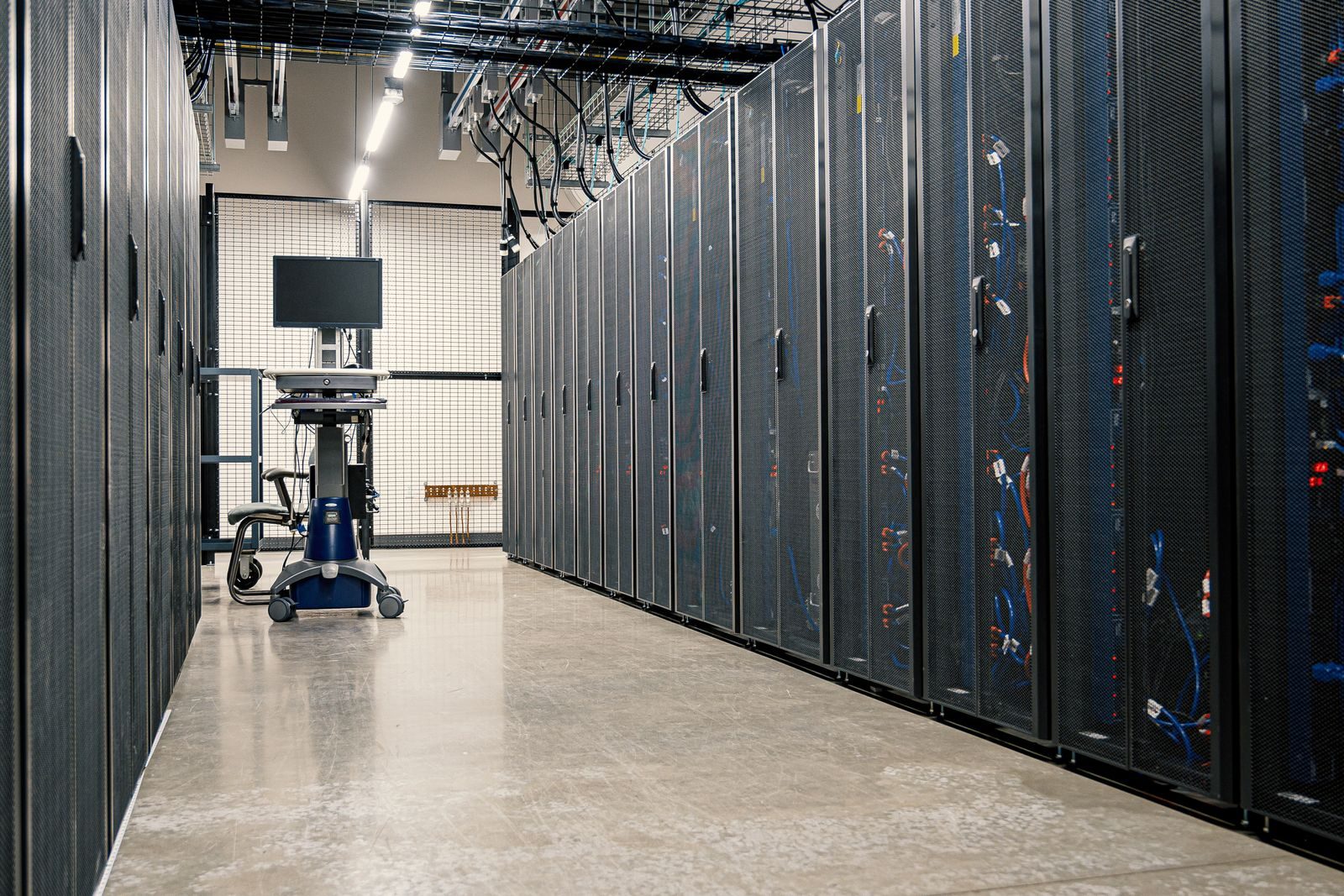 A data-center corridor lined with server racks; no people, screens off.